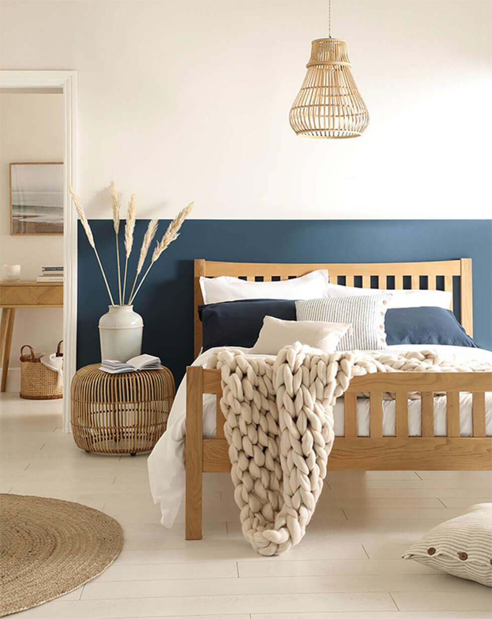 White bedroom with oak wooden bed in a coastal-style interior.