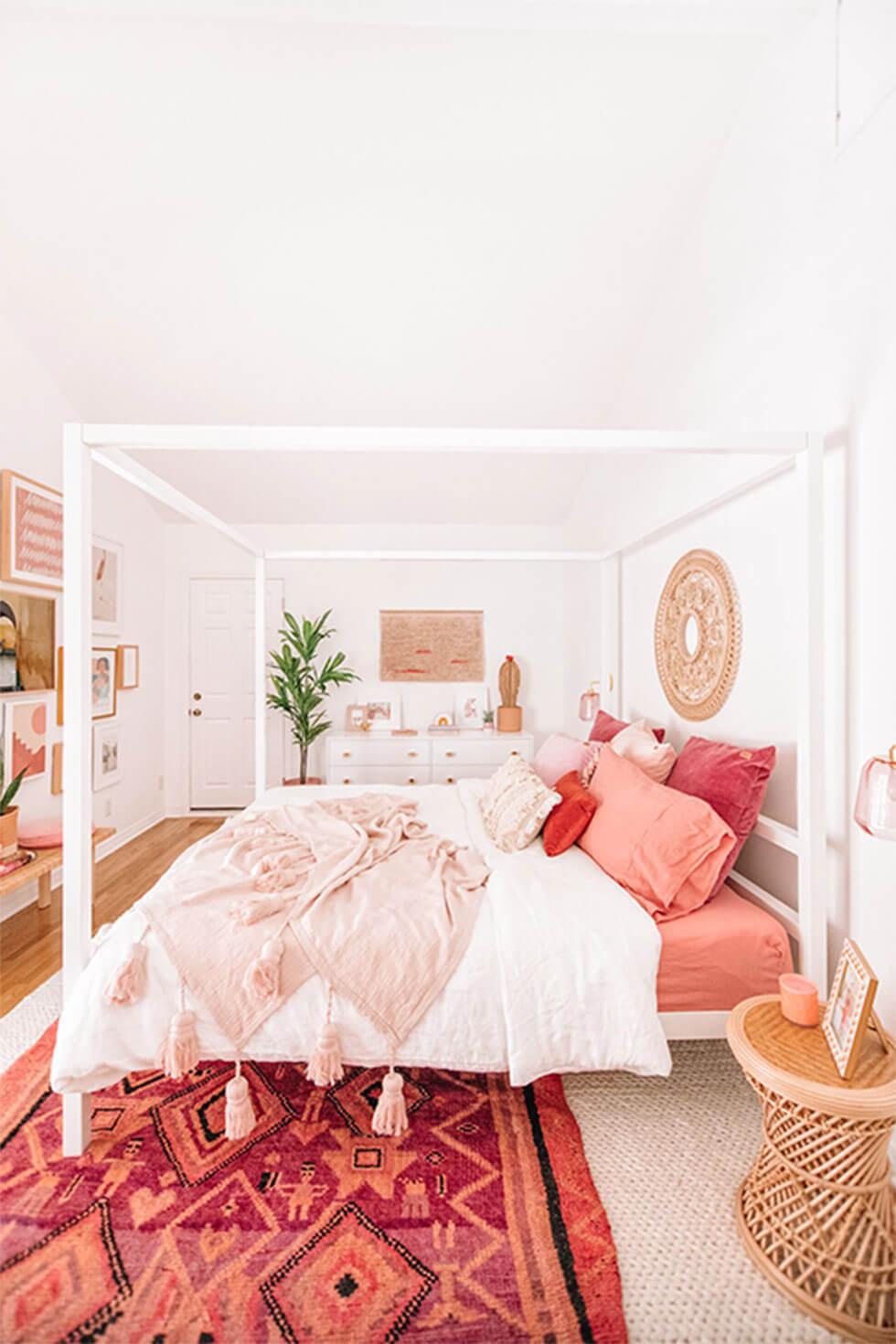 White bedroom with pink decor and canopy bed.