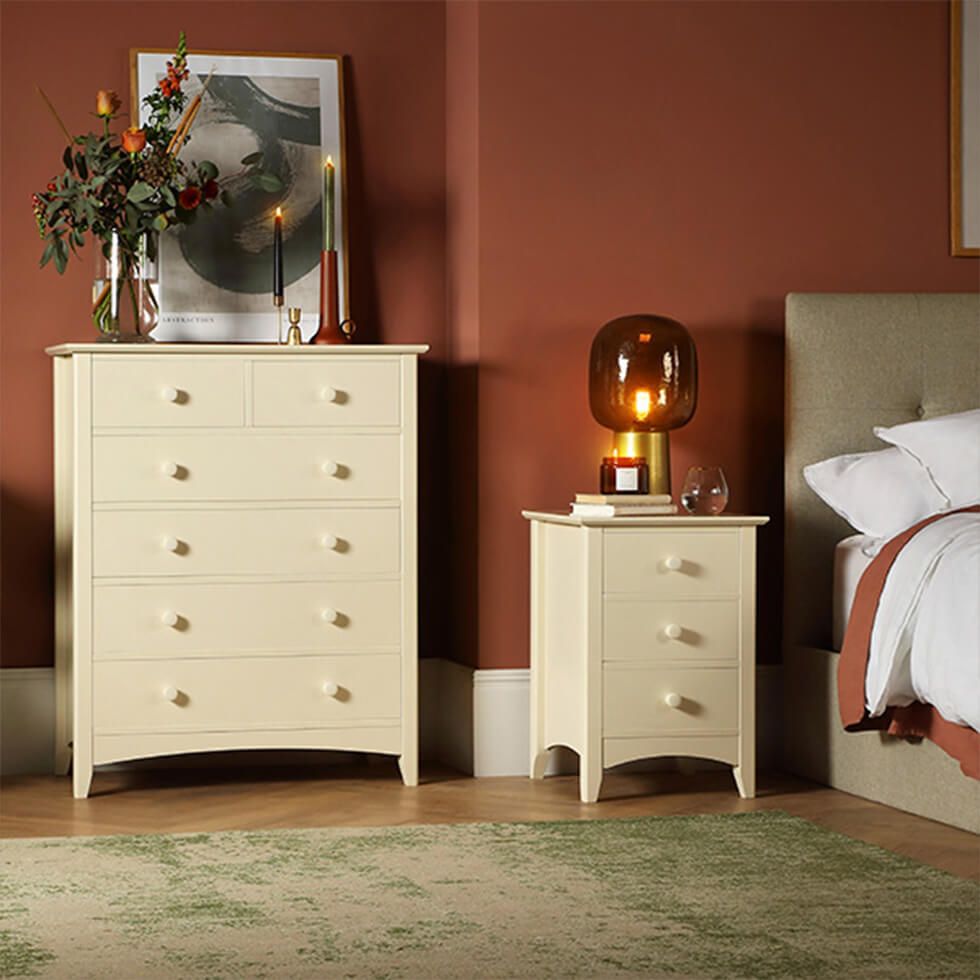 A bedroom with warm brown walls styled with cream furniture and soft lighting