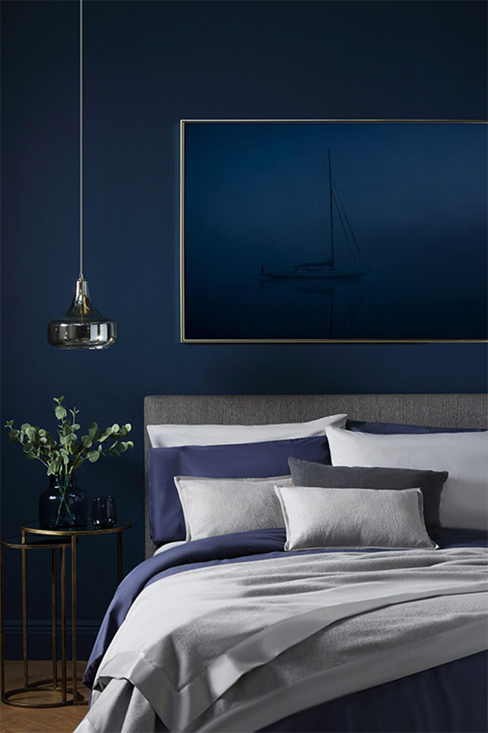 Navy bedroom with grey and blue bedding and gold accents