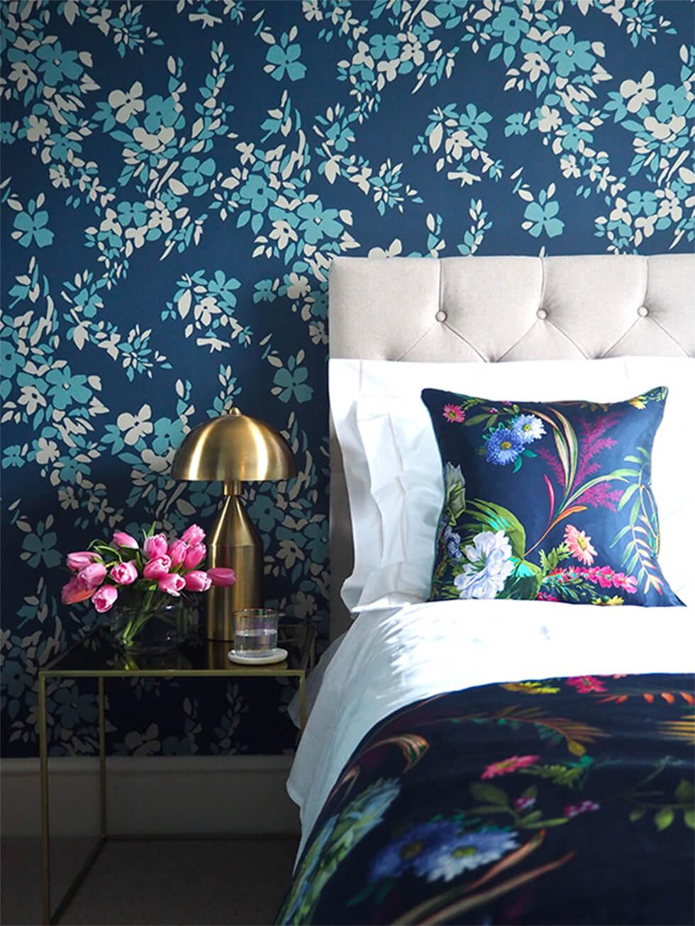 Maximalist blue bedroom with floral wallpaper and colourful bed linen