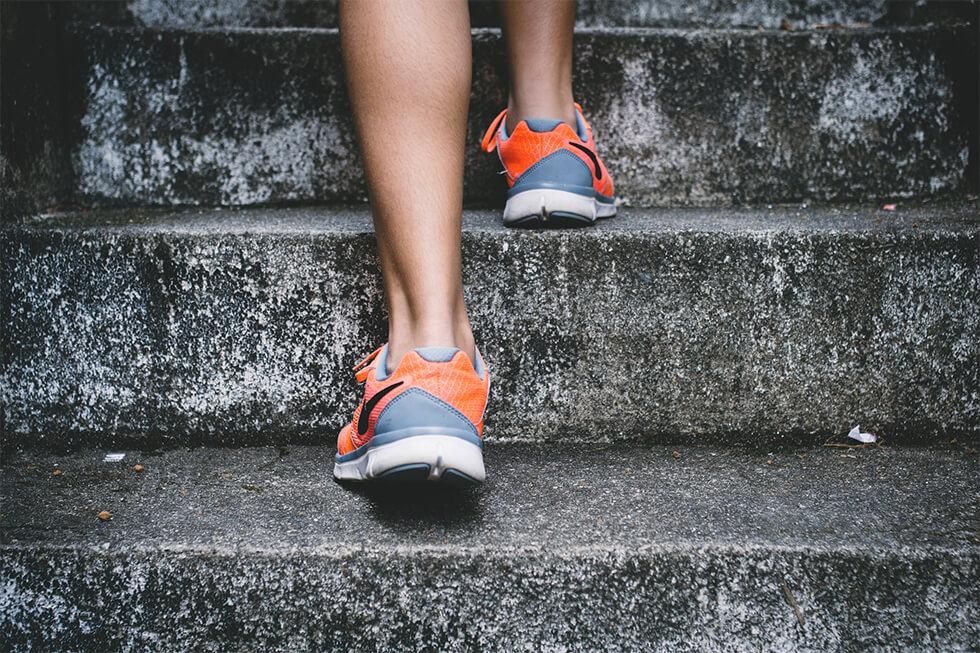 person wearing orange running shoes on stairs.