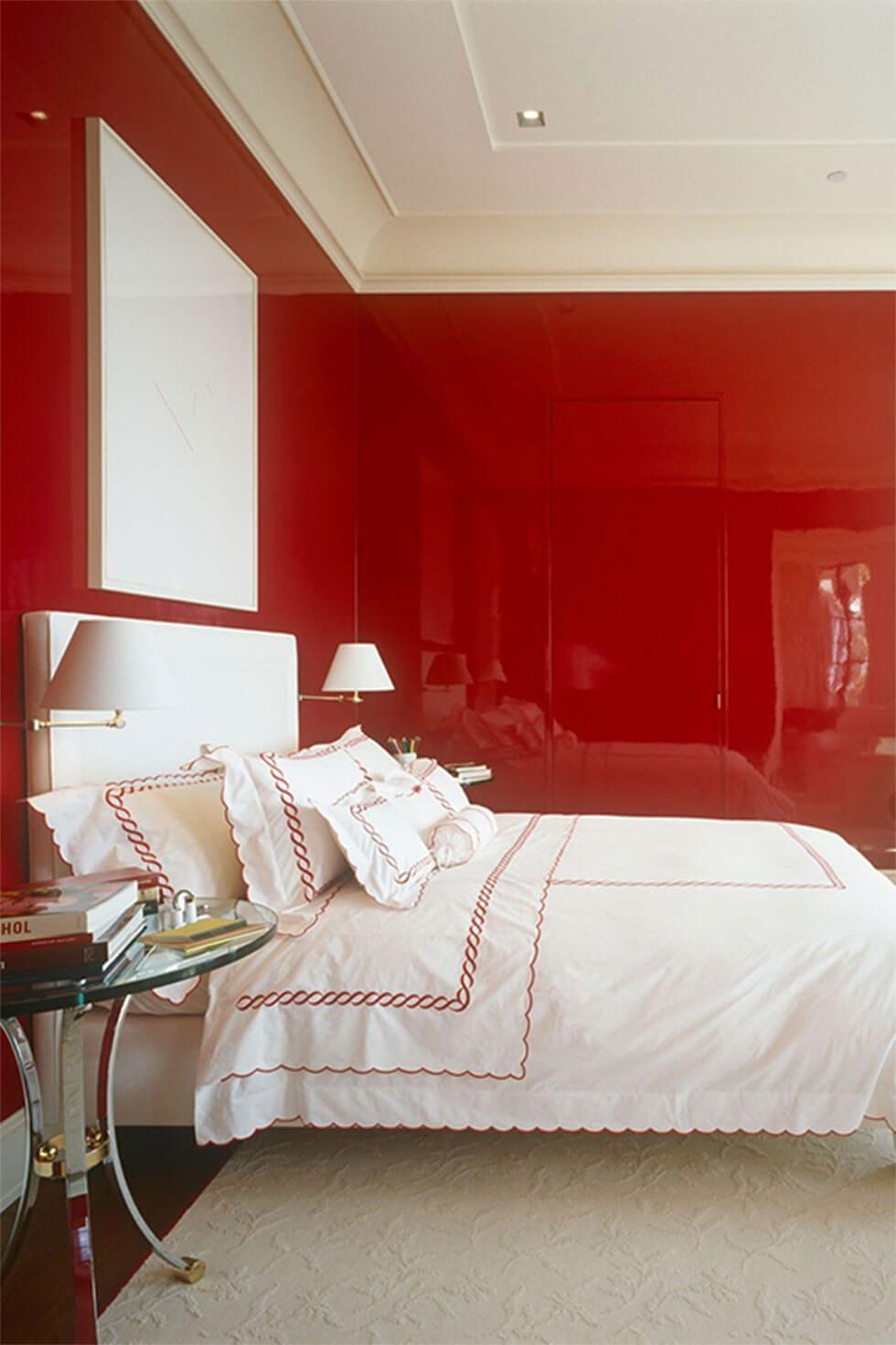 Modern bedroom with glossy red walls, matte white ceiling, and a white bed