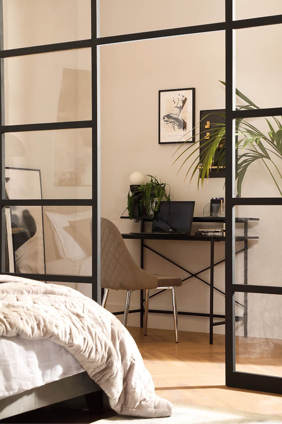 A home office in a contemporary bedroom with glass partitions as a room divider