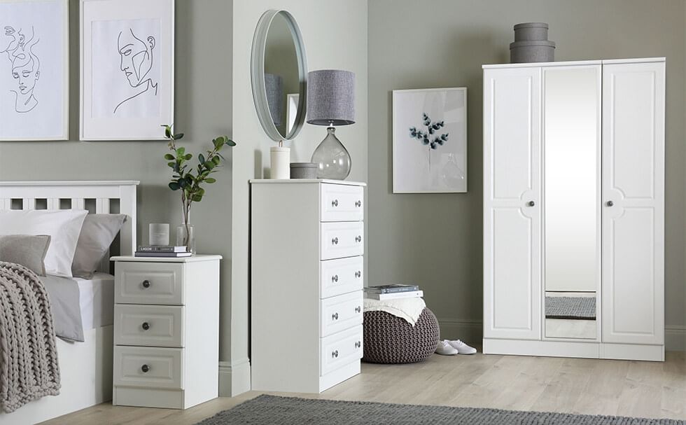 A classic white bedroom furniture set that consists of a 3 door wardrobe with full length mirror, a chest of drawers and a bedside table
