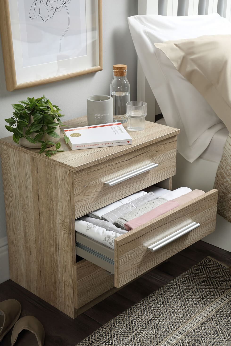 A wooden bedside table with clothes folded in Marie Kondo's Konmari method