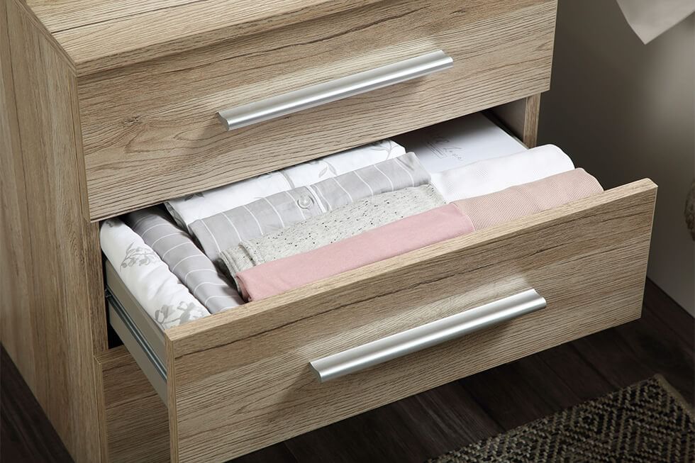 A close up of clothes folded in Marie Kondo's KonMari method and stored in a wooden bedside table