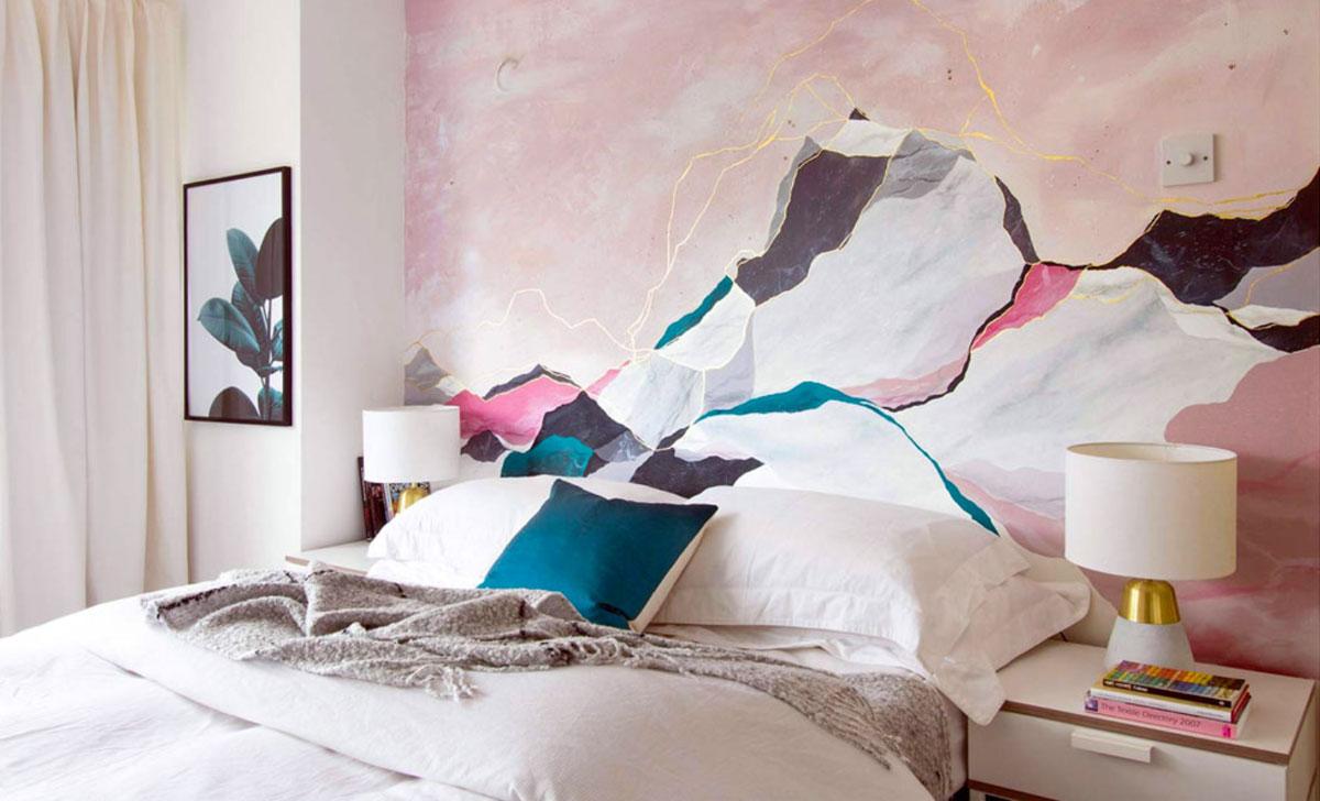 A pale pink bedroom with contrasting teal pillows.