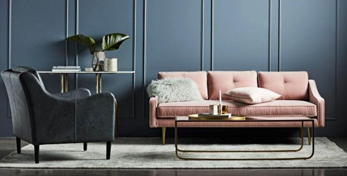 A pale pink sofa set against a dark teal wall.