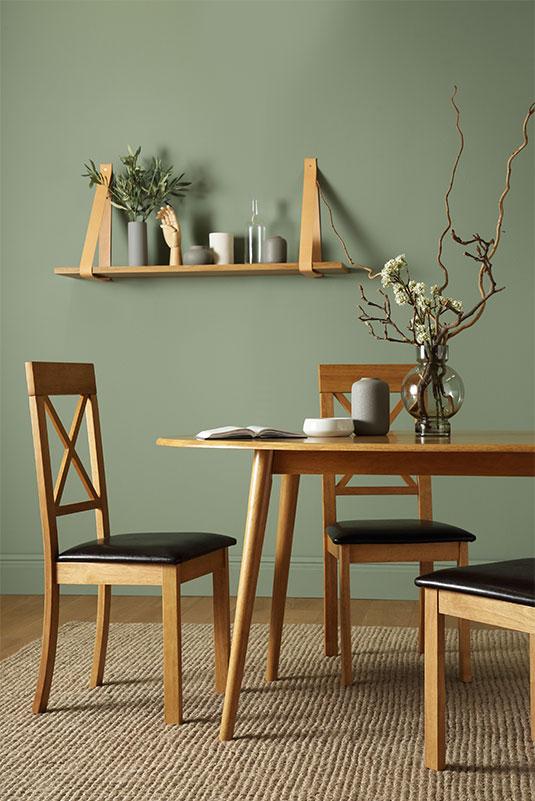 Wooden dining set with leather strap shelf against a sage walll