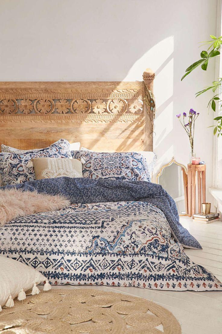 A bedroom with a wooden headboard, and a bohemian, blue bedspread.