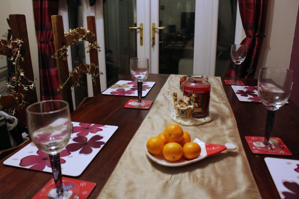 Wooden dining table set for a meal, with a plate of oranges.
