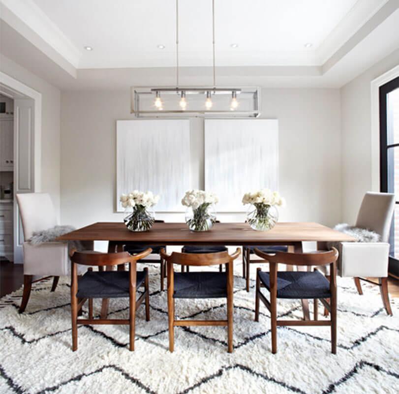 Elegant dining room with a mix of wooden and fabric chairs, a wooden table, and geometric rug.