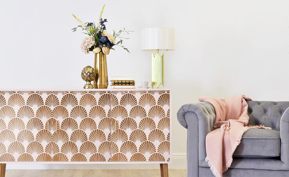 White and gold sideboard with a grey Chesterfield armchair and accessories.