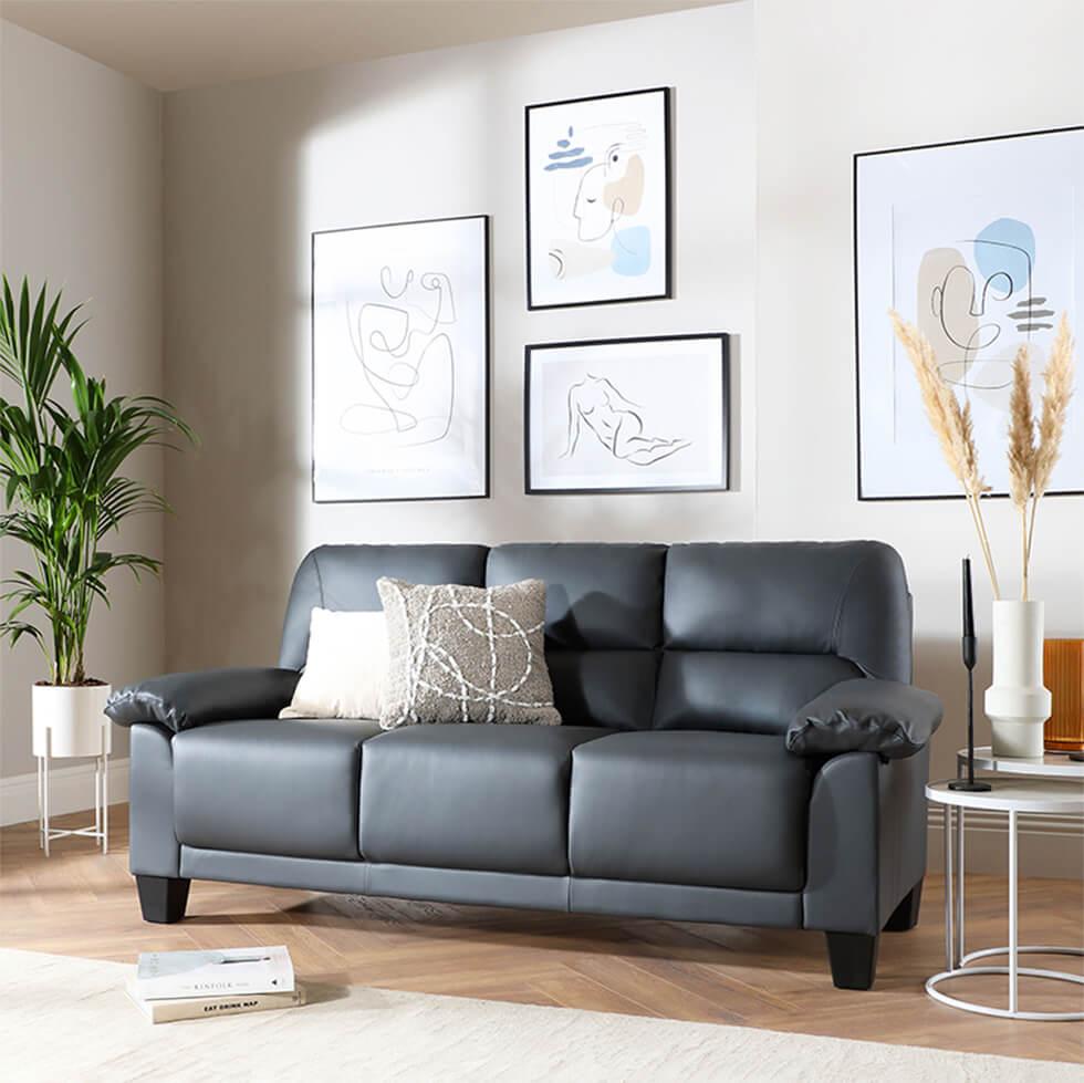 Grey leather sofa in a living room with black framed art and accessories