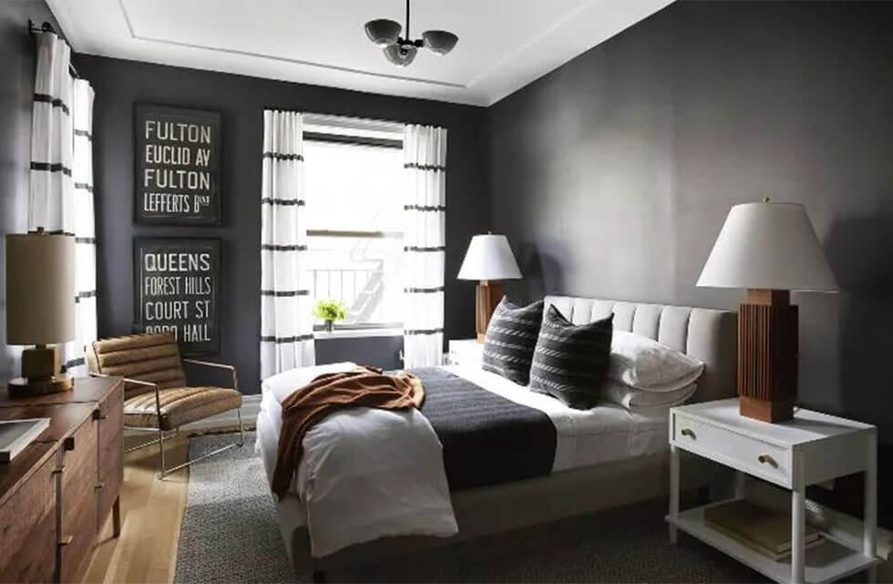 Black and white bedroom with wooden lamps, wooden chest of drawers and wood flooring