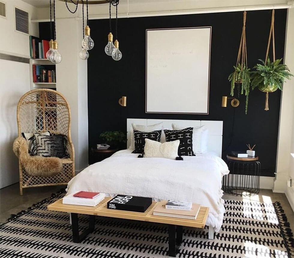 Black and white tropical bedroom with rattan chair, macrame plant hangers and indoor plants