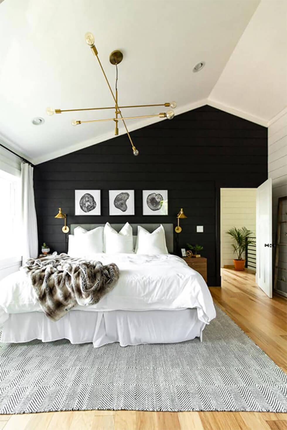 Modern black and white bedroom with rustic touches, a gallery wall, wood floors and a brass chandelier