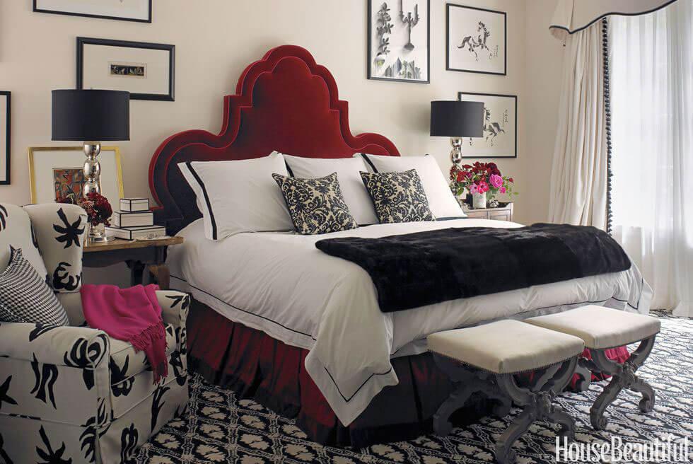 Black and white room with upholstered red velvet bed and printed armchair