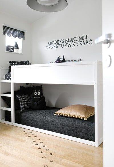 White child’s bed with storage space, and black decor and decals.