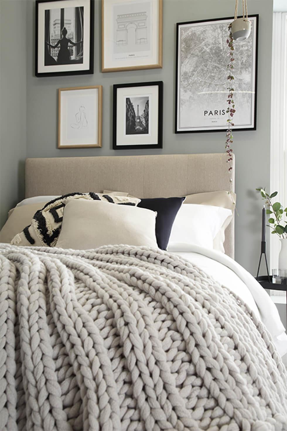 Fabric bed with knitted blanket and framed gallery wall