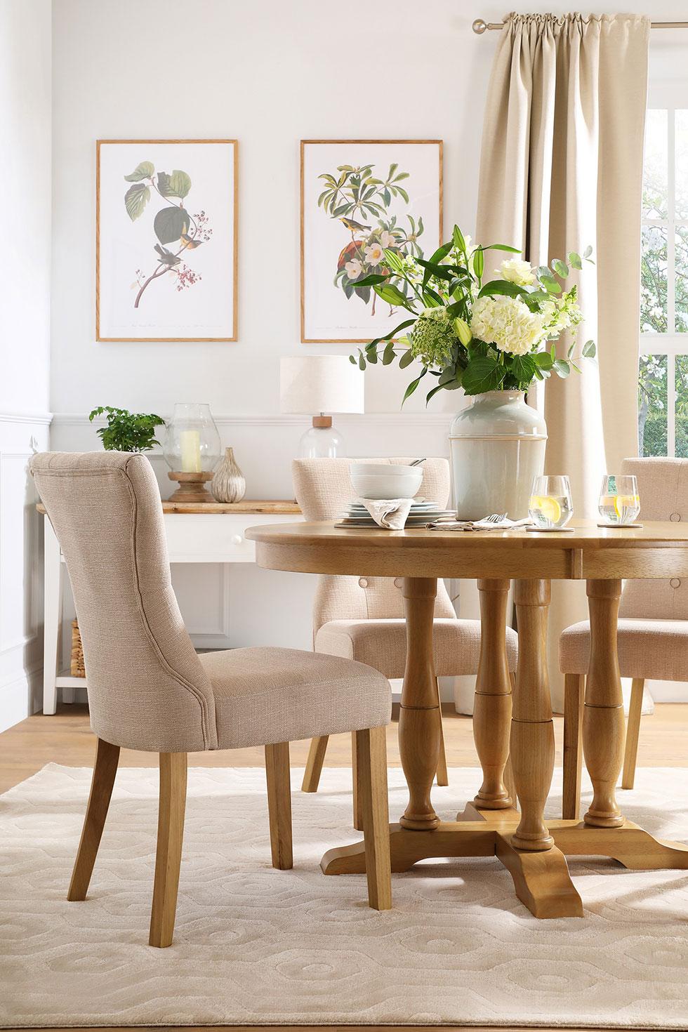 Neutral dining room with round wooden dining table and light fabric chairs