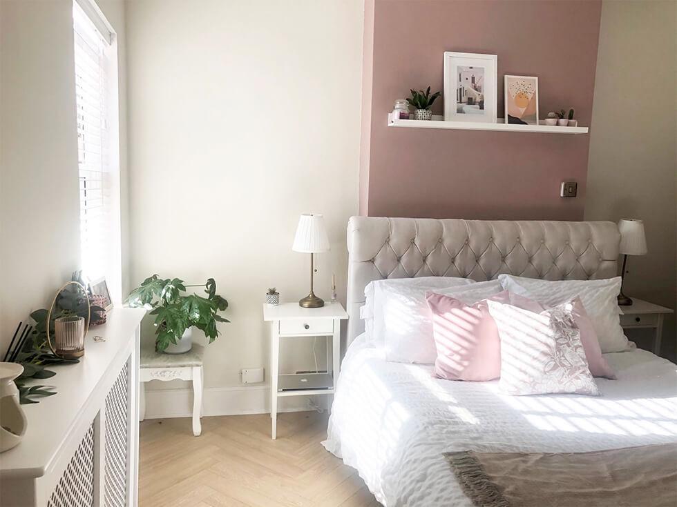 Cosy and elegant bedroom with tufted Chesterfield bedframe and pink feature wall