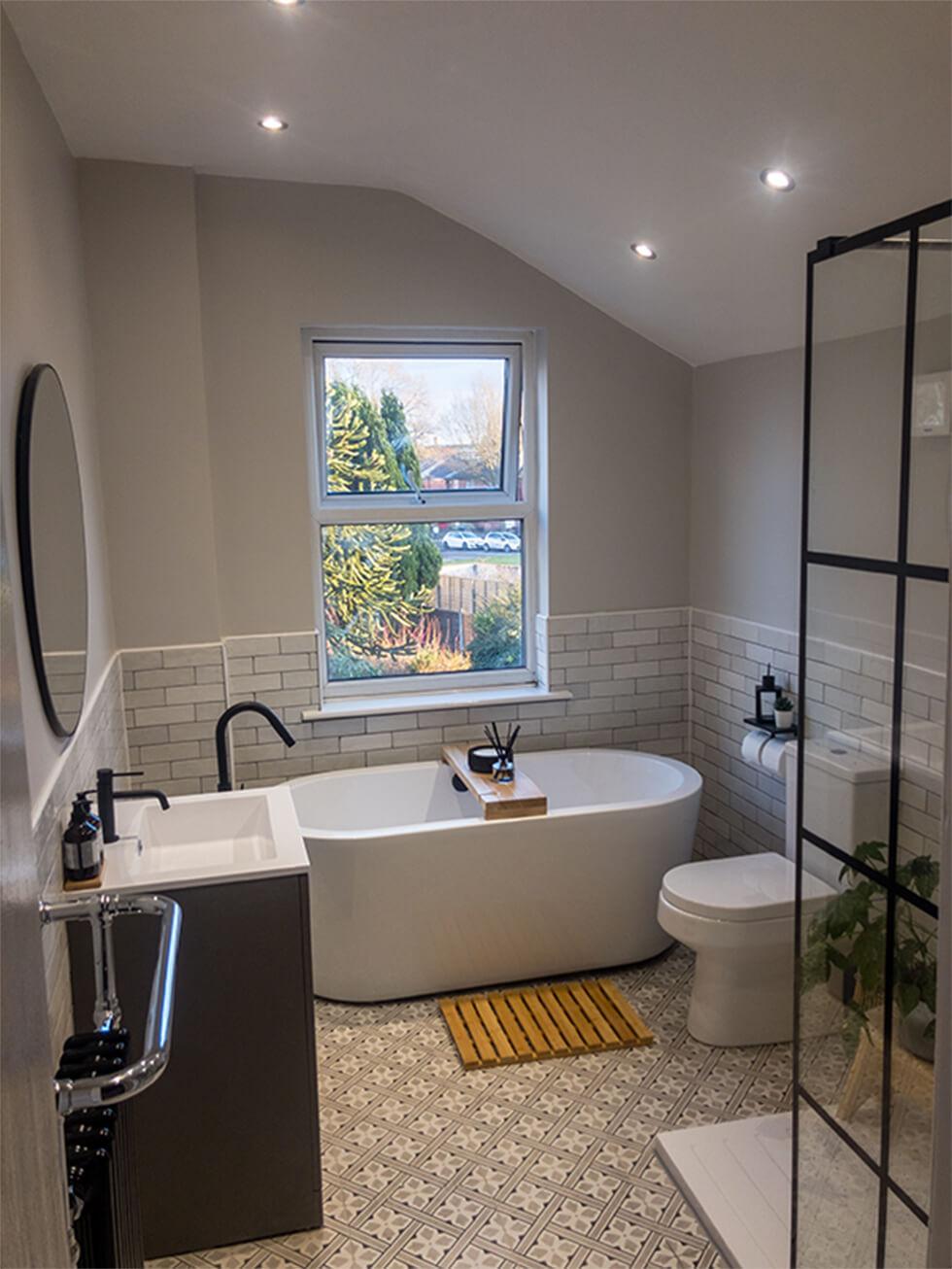 Master bathroom with white bathtub, tiles and black accents