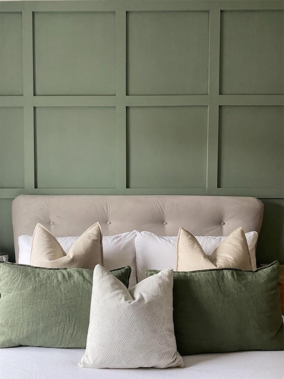 Close up shot of velvet bed headboard, wall panelling and cushions