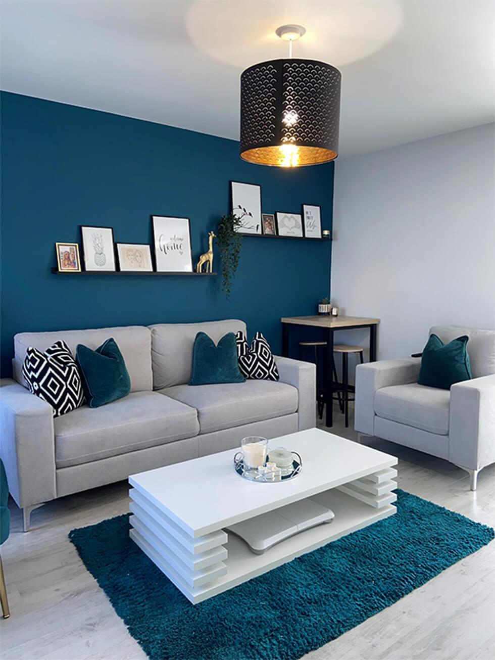 living room with teal feature wall and modern grey sofa and armchair