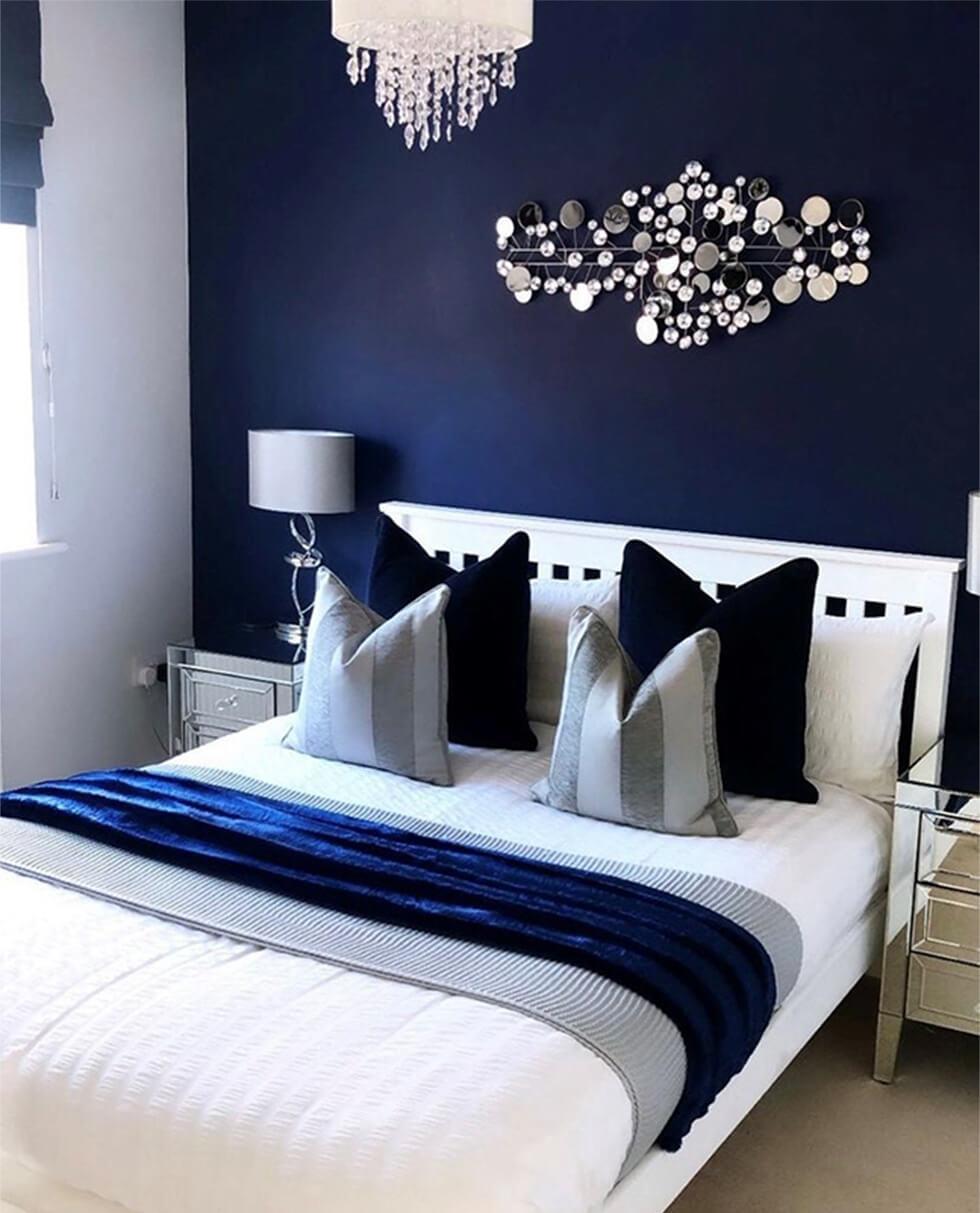 bedroom with dark blue walls and mirrored bedside tables