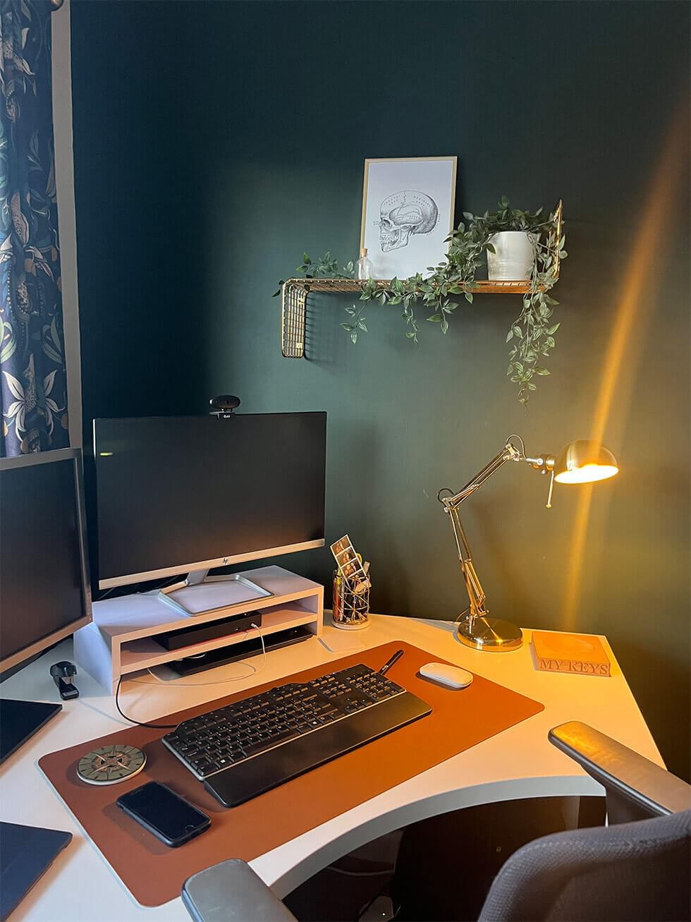 Dark green home office with artwork and greenery