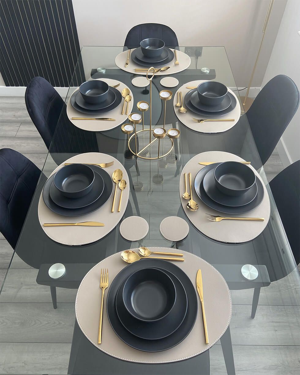 Black dining set with gold cutlery and beige placemats