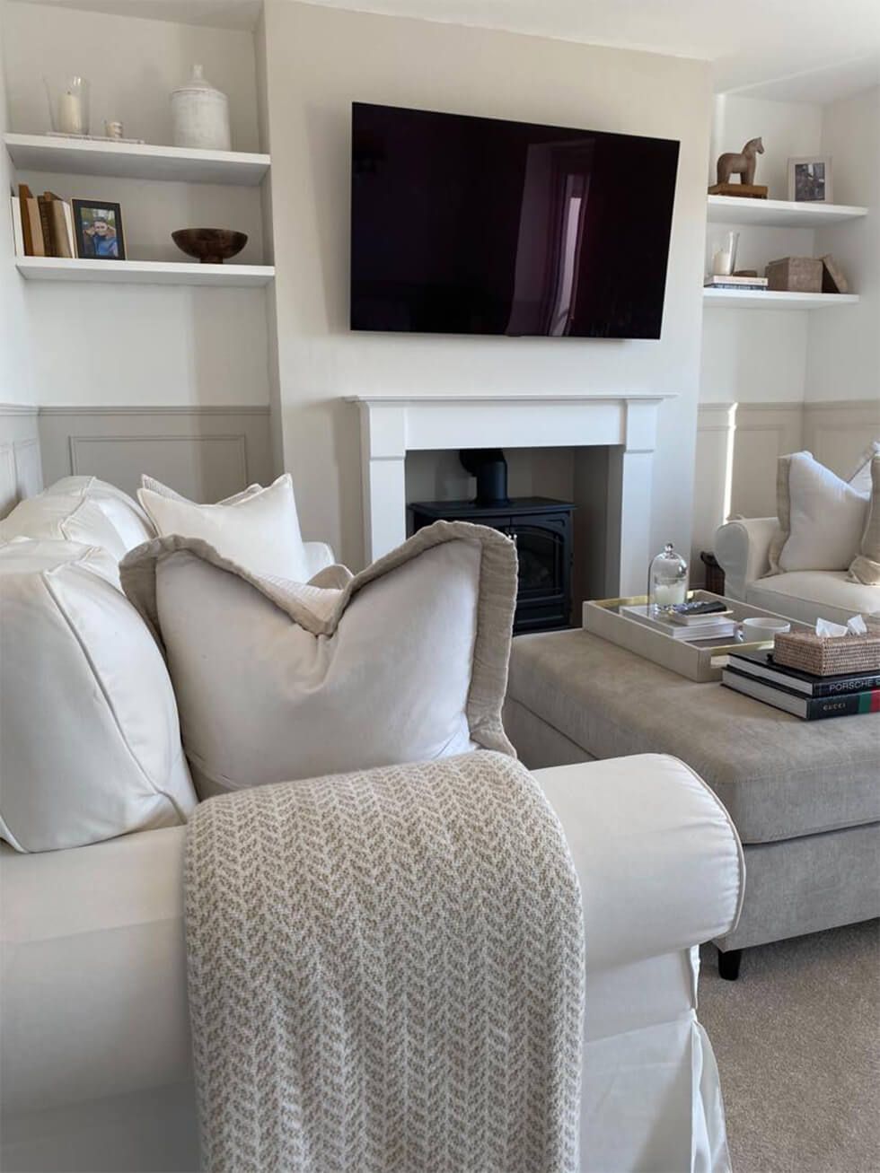 A cosy neutral living room with comfy cushions and open shelving at the back