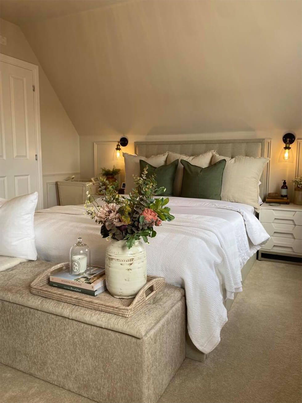 A sloped ceiling bedroom with a tufted bed fitted with white linens