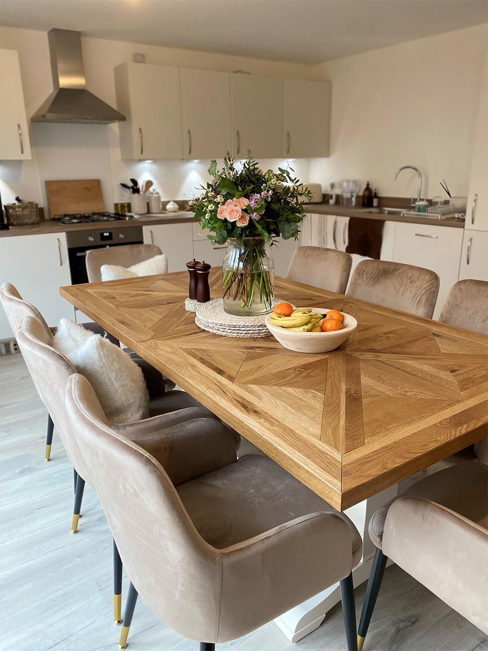 A neutral kitchen and dining area with a large wooden table and beige velvet chairs
