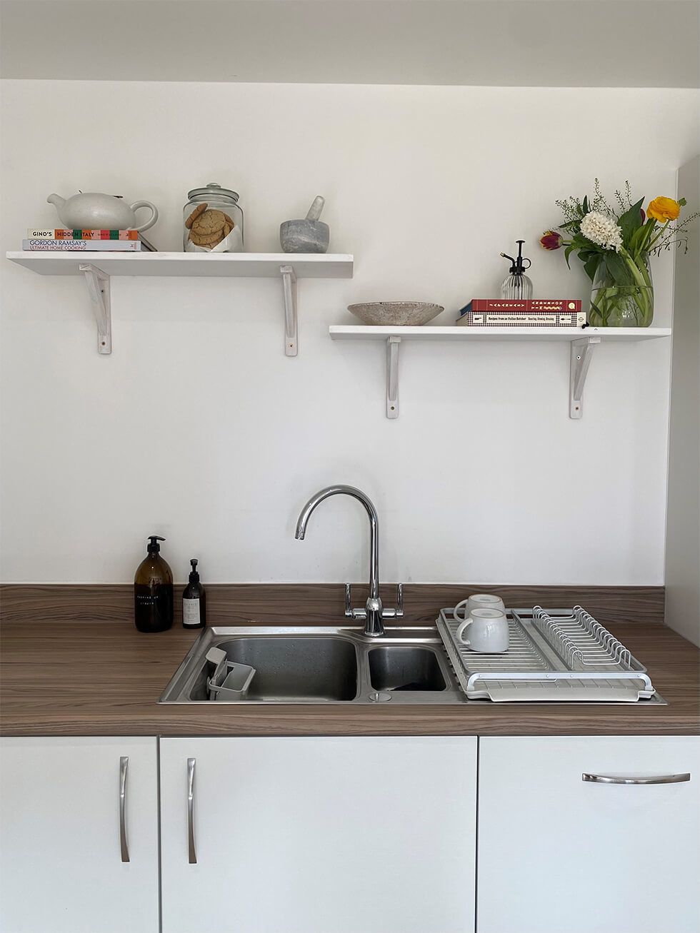 A kitchen sink with open shelving above it