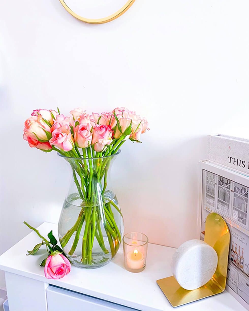 A bouquet of pink roses next to a candle