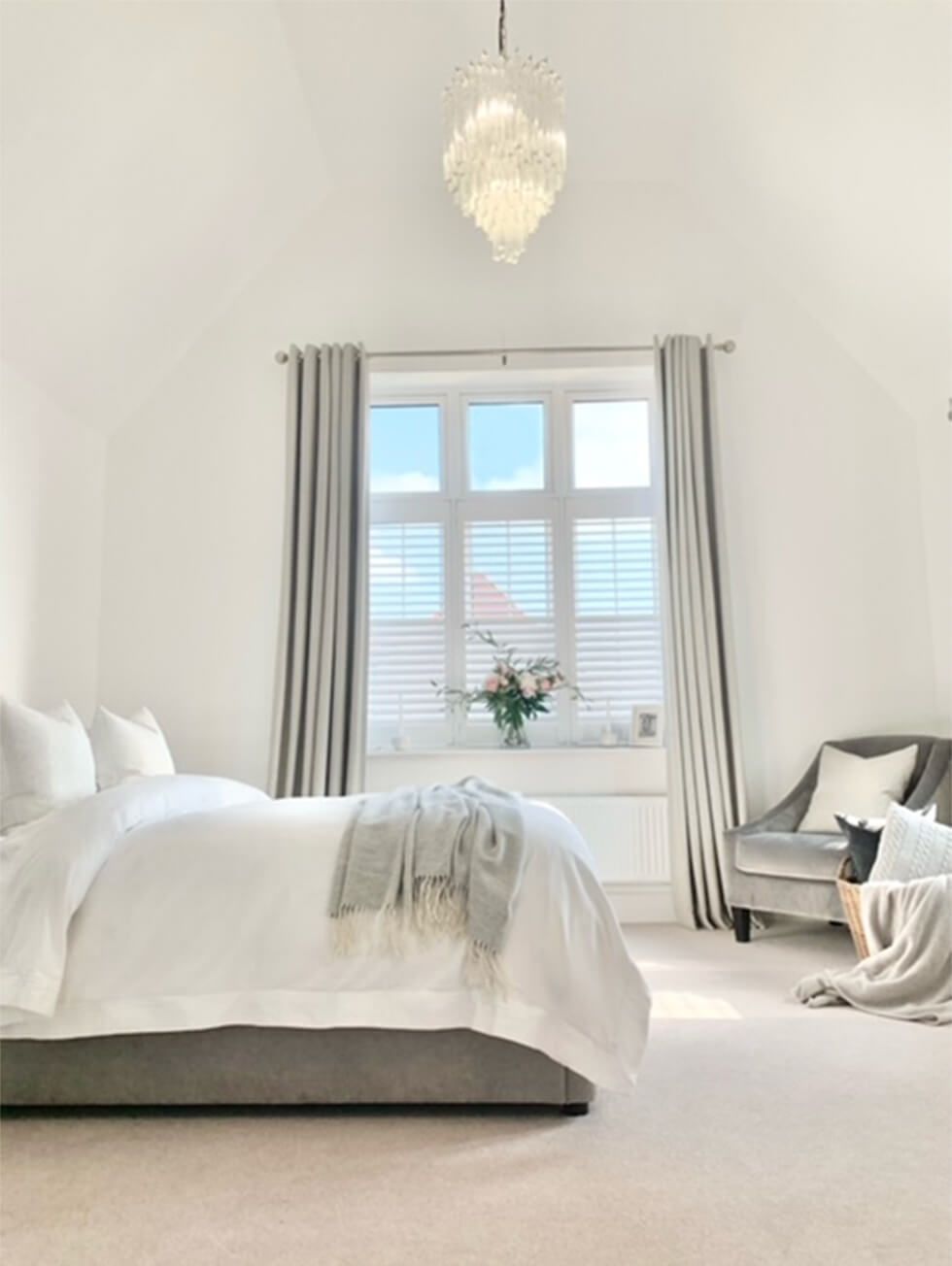 Elegant neutral bedroom decorated with an armchair, double bed and chandelier