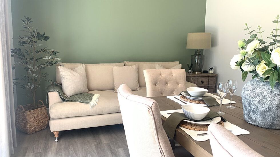 Casual family room with beige sofa and green wall