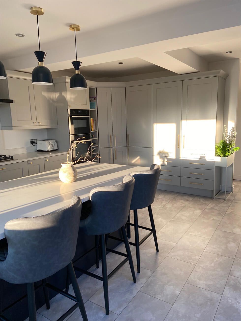 A spacious kitchen featuring modern cabinets and a centre island with bar stools