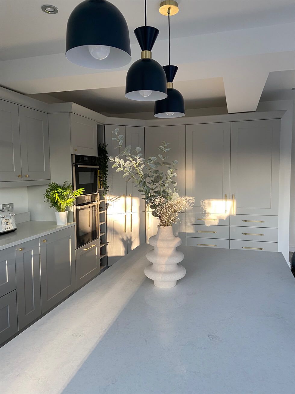 A light grey kitchen with a big centre island and chic pendant lamps