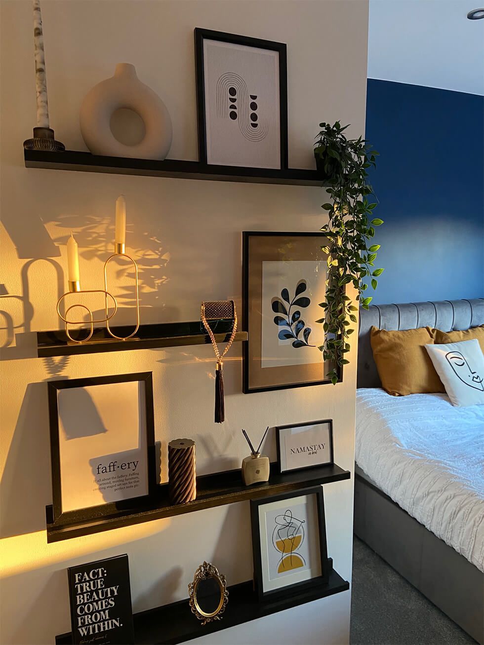 A bedroom with tastefully decorated floating shelves and a navy accent wall
