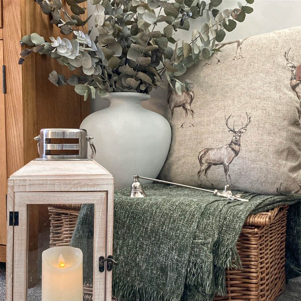 A faux candle, vase, cushion and grey throw