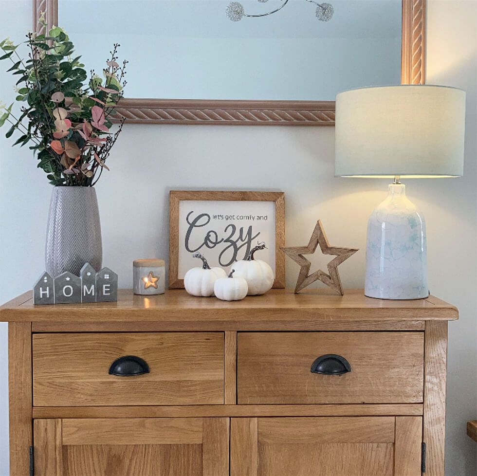 Wooden sideboard with a wooden star ornament, candles, vase and lamp