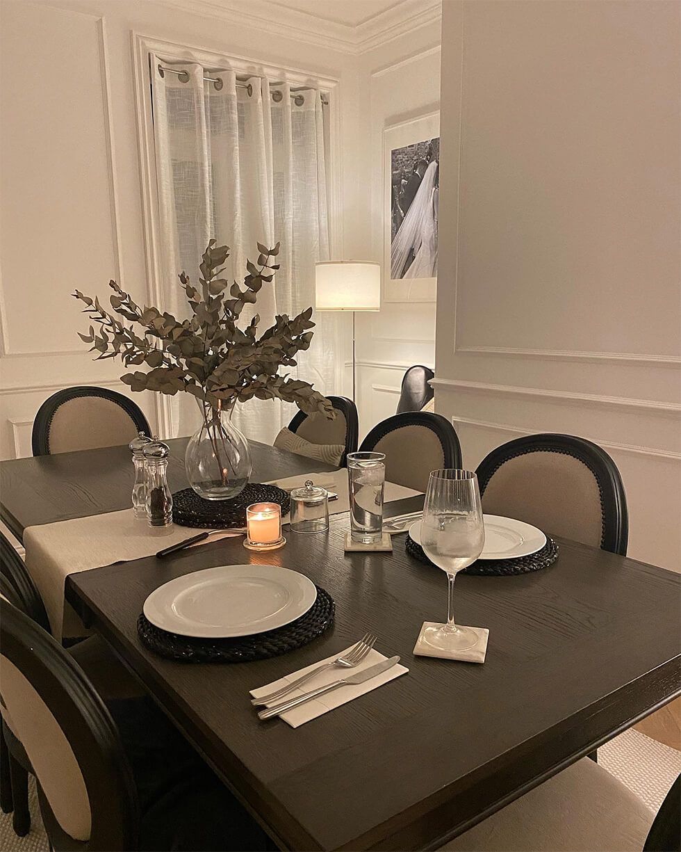 Close up of dining room with white panels, grey wood dining table and wooden fabric chairs