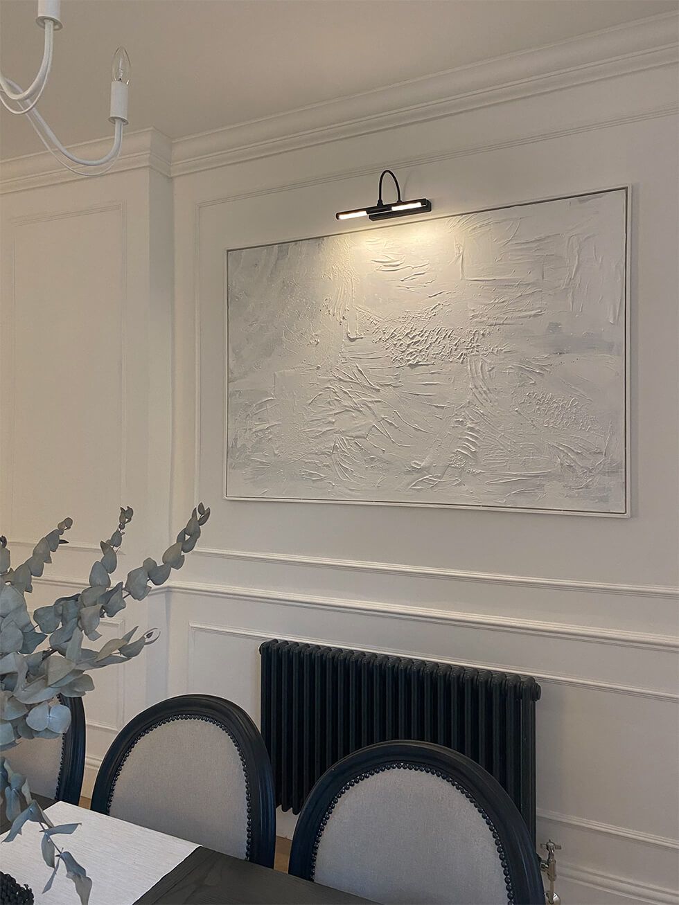 White abstract art piece in dining room with wall panelling