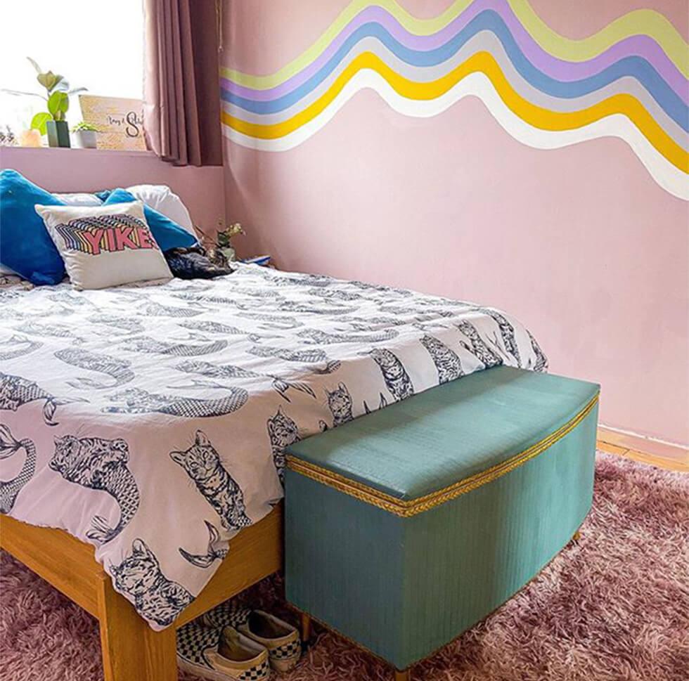 wave mural in a pink bedroom with a shaggy pink rug and teal ottoman