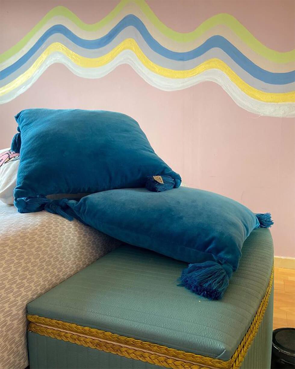 blue pillows in a pink bedroom with a wall mural