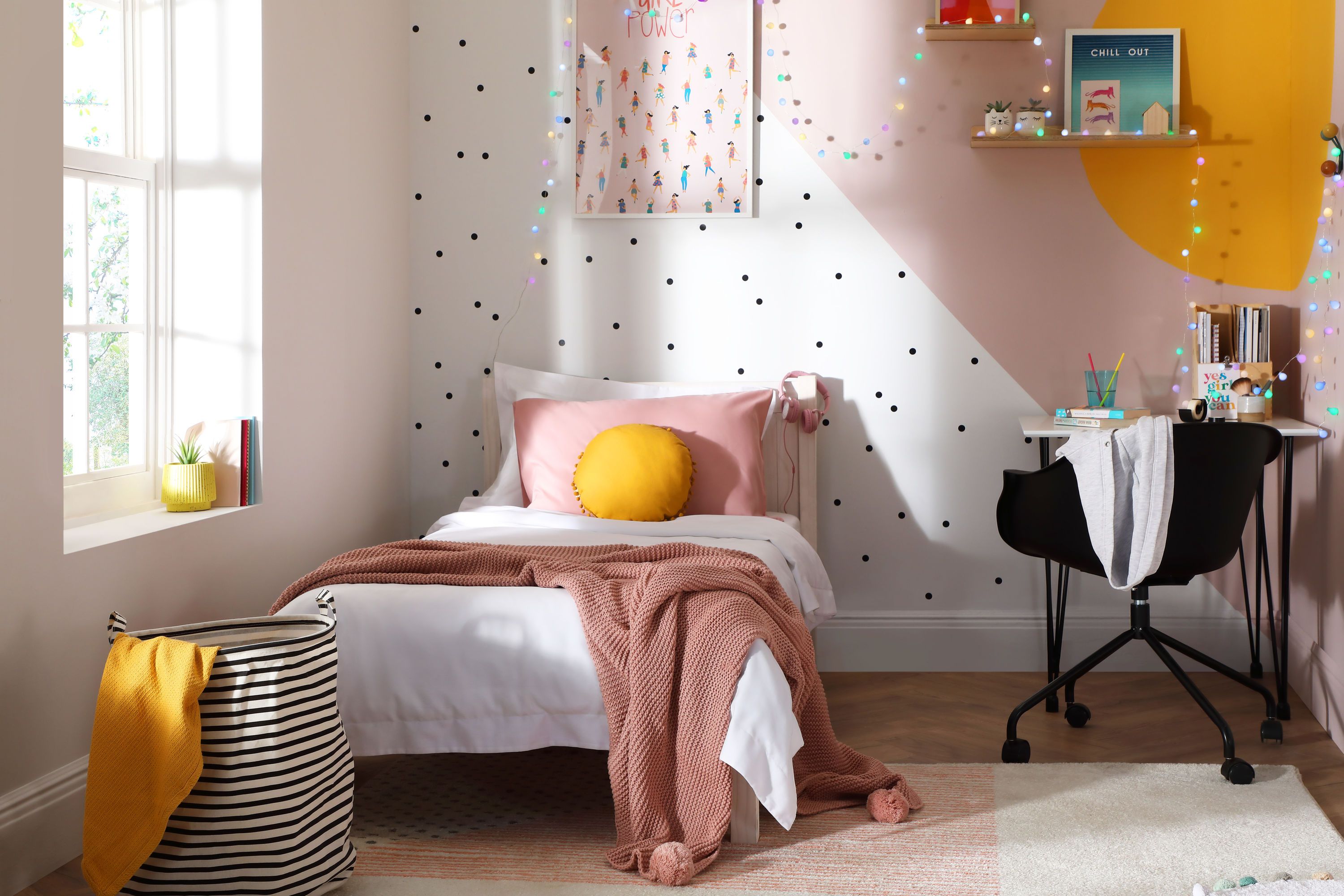 Bold yellow and pink feature wall with polka dots in a modern kids bedroom